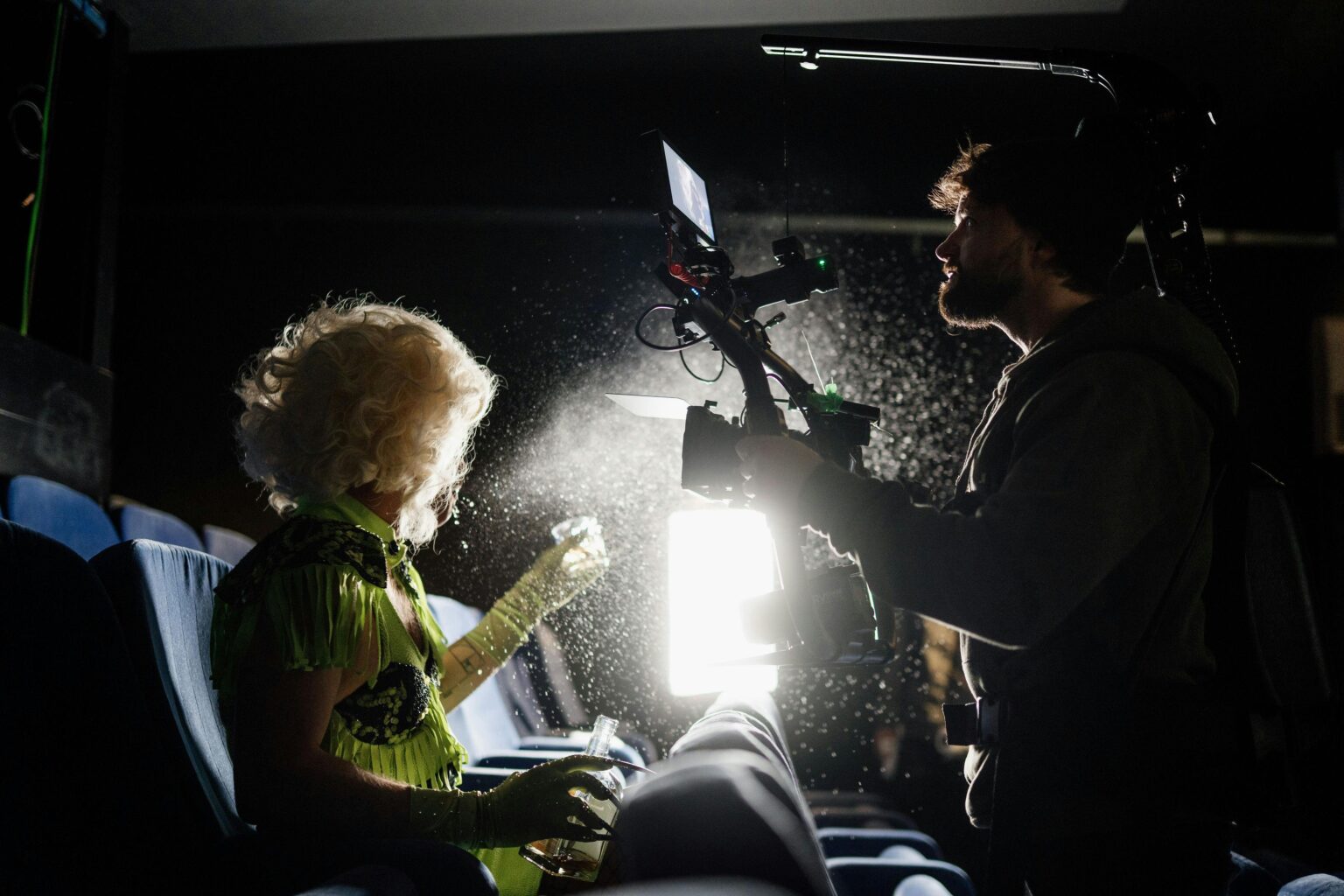 Filmmaker capturing a scene in a dimly lit theater with dramatic lighting effects.